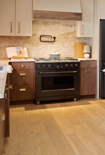 Modern kitchen with black stove, european white oak flooring and warm wood cabinets.