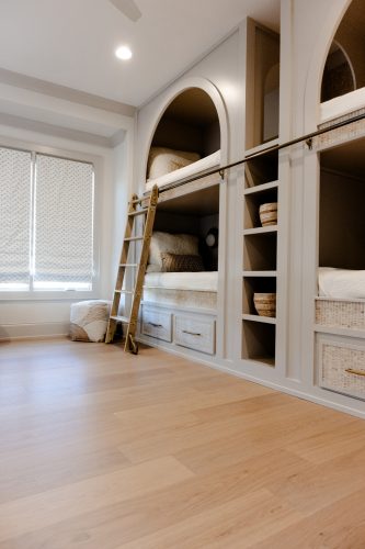 Modern, cozy bedroom with custom bunk beds and natural oak flooring adding warmth and texture.