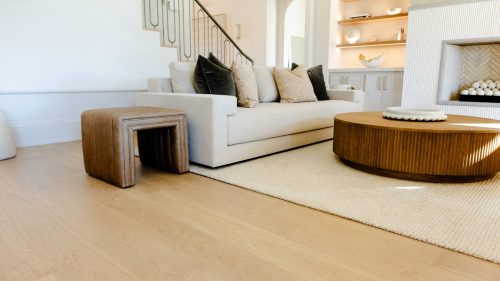 Modern living room with light oak floors, neutral-toned furniture, and soft natural lighting.