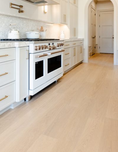 Sleek kitchen design with wide-plank oak floors, quartz countertops, and brushed brass fixtures.
