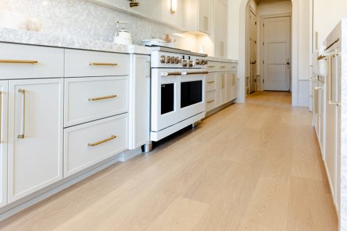 Open-concept kitchen with light oak floors, white cabinets, and brushed gold fixtures for a modern yet timeless feel.