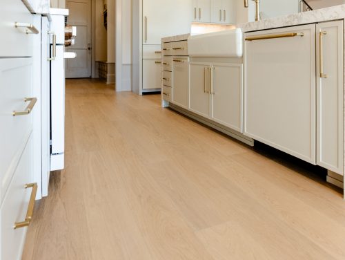 Bright and sophisticated kitchen with pale oak flooring and gold-accented cabinetry.