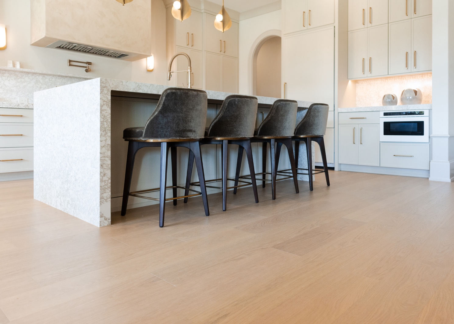 Bright kitchen featuring light oak floors, white cabinetry, and brass hardware.