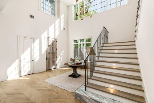 English tudor entryway with tall ceilings, wood flooring, and bright light.