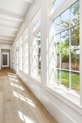 Window-lined walkway in English Tudor home, featuring Vintage Loft Bowery flooring.