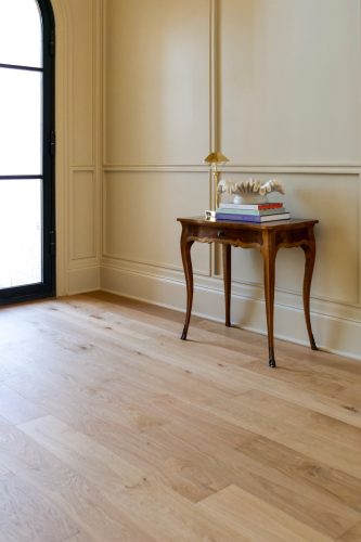 White oak flooring in entry with paneled walls and antique wood table