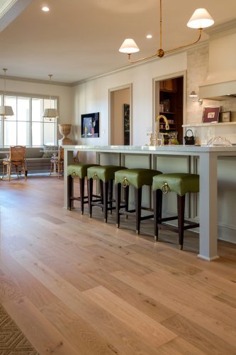 Wide plank 1875 white oak flooring in a Collierville custom kitchen with green stools and brass fixtures