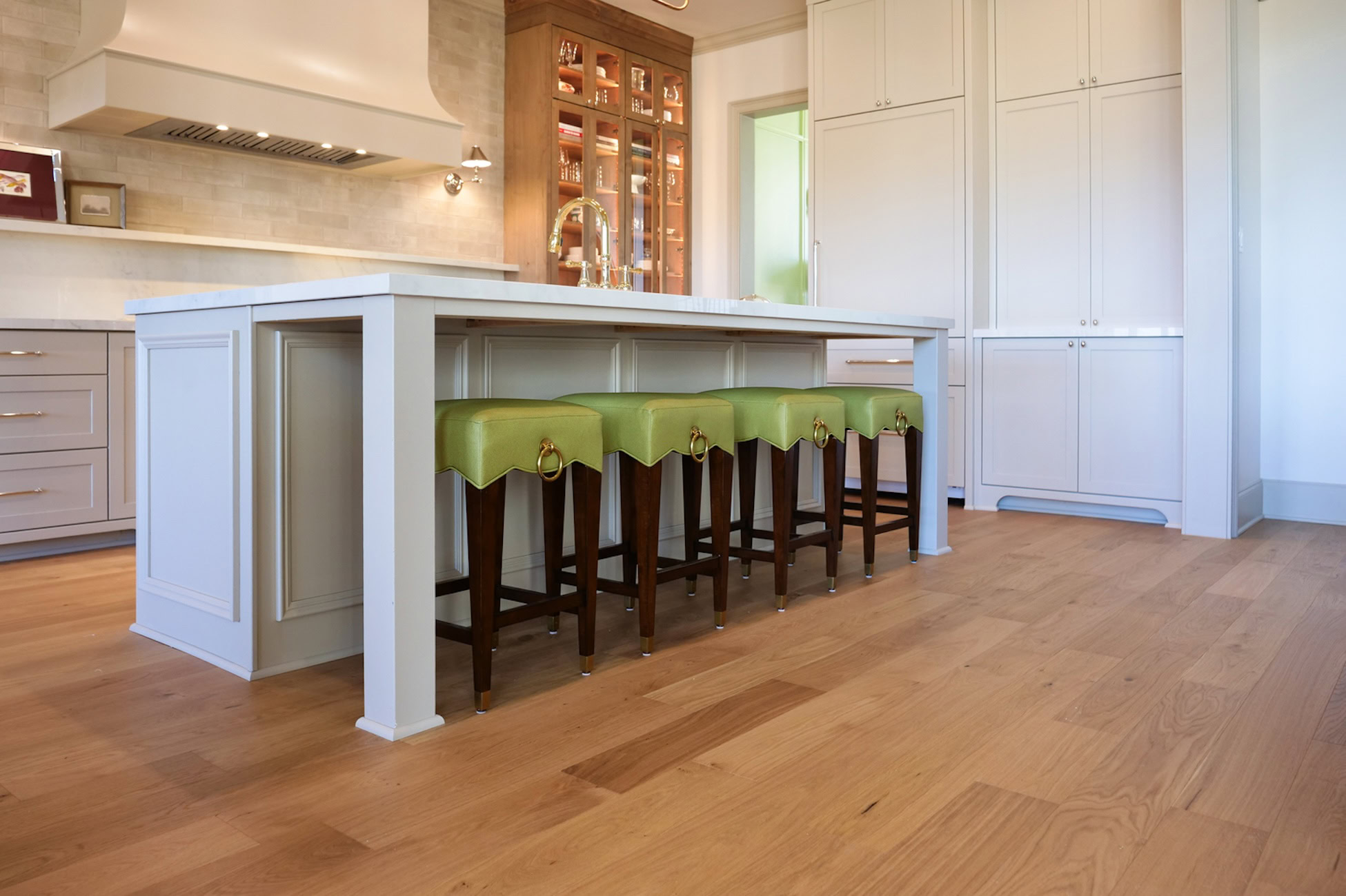 Memphis Kitchen with natural white oak hardwood flooring, large island, and upholstered green bar stools