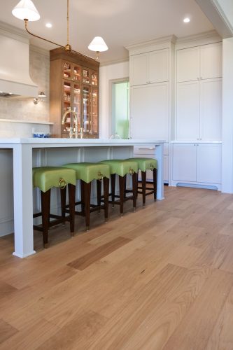 Warm modern kitchen designed by Maggie Clarke featuring wide plank hardwood floors, mixed metals, and custom cabinetry