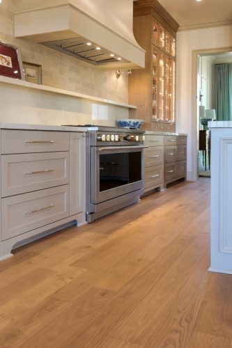 White oak flooring grounding a custom kitchen with brass accents and neutral cabinetry
