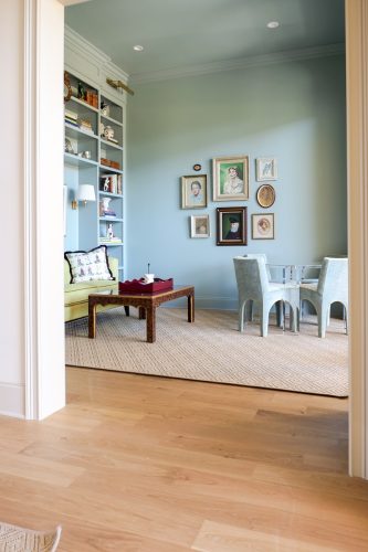 Cozy library-inspired sitting room designed by Maggie Clarke with hardwood floors and layered lighting