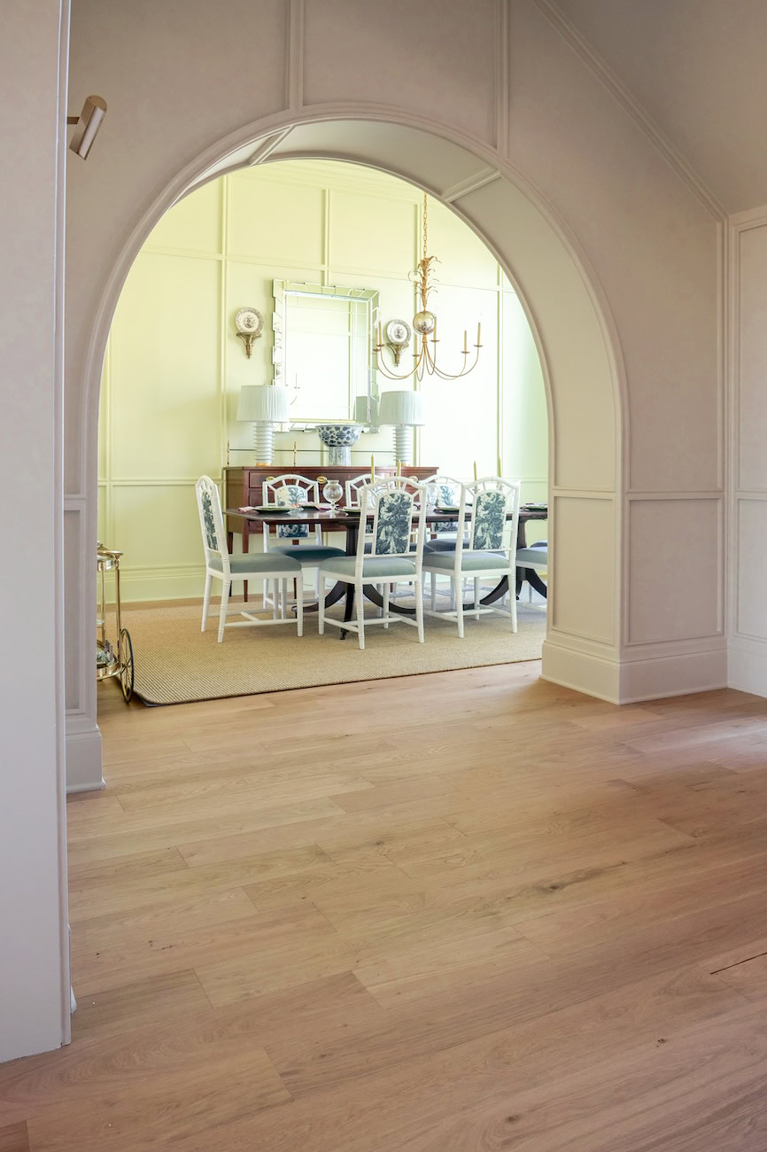 Arched doorway framing a chartreuse dining room with 1875 Surrey white oak flooring