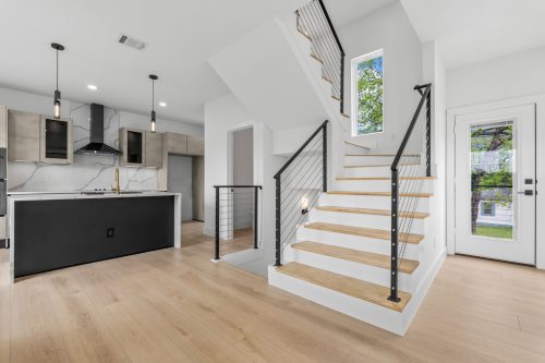 Modern kitchen with waterfall island, gold faucet, and light wood composite flooring