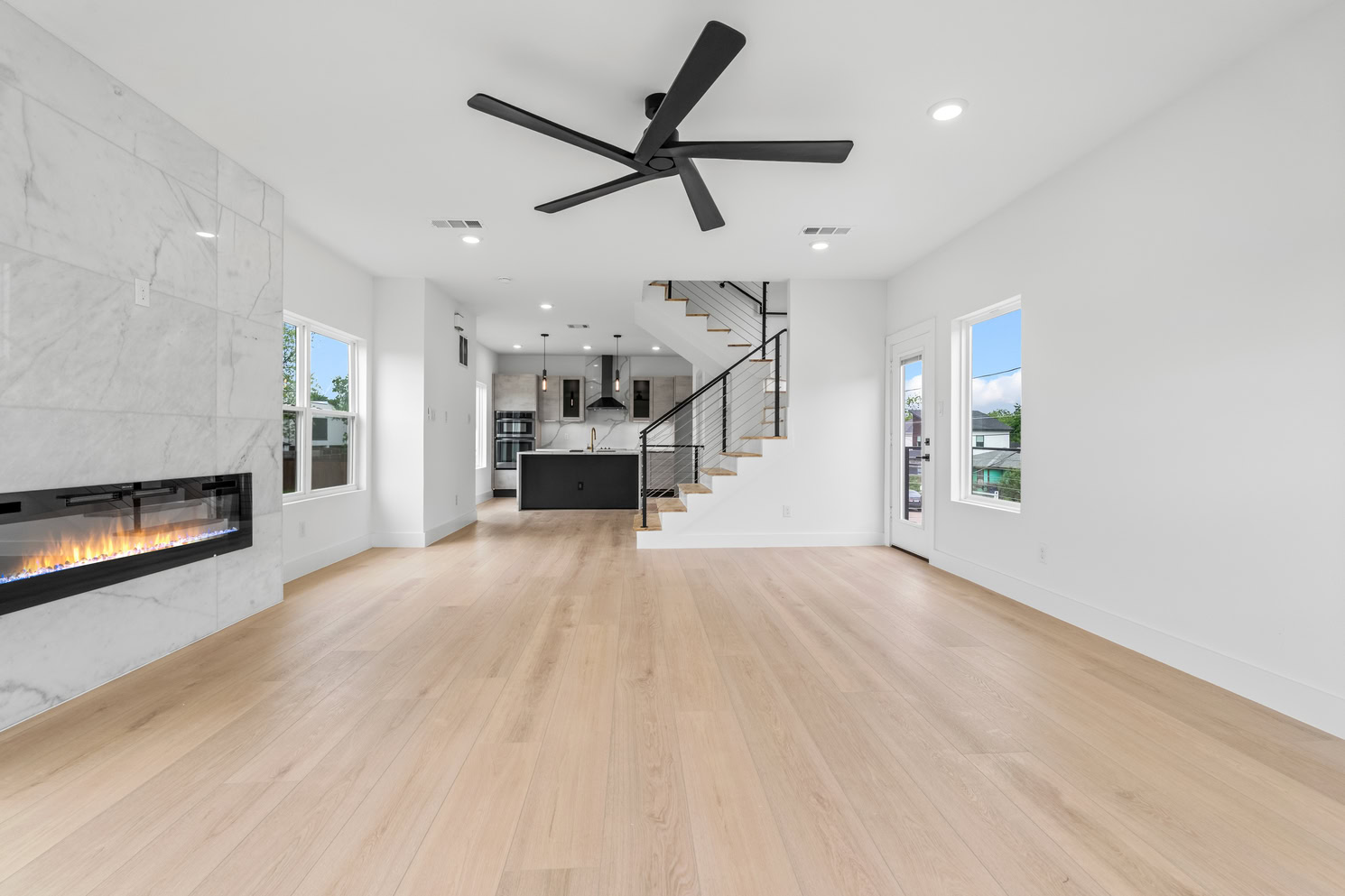 Modern living space with floor-to-ceiling tile fireplace and wide plank wood composite floors