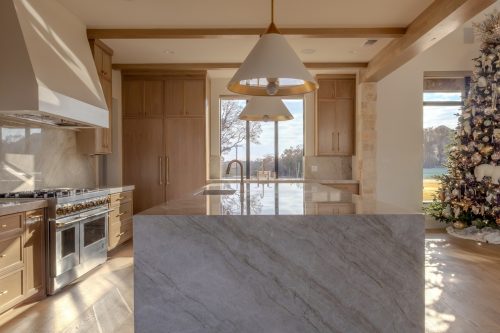 Open-concept kitchen featuring natural wood cabinets, brass accents, and seamless hardwood floor continuity
