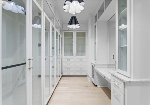 Large primary closet with bright cabinets, statement lighting and Silvian Laakso flooring.