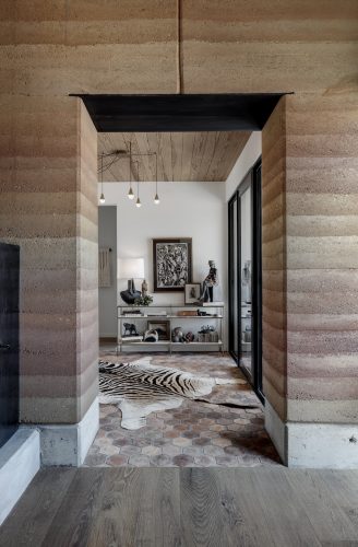 Modern entry with clean lines, textured materials, and wood floors reflecting the surrounding landscape