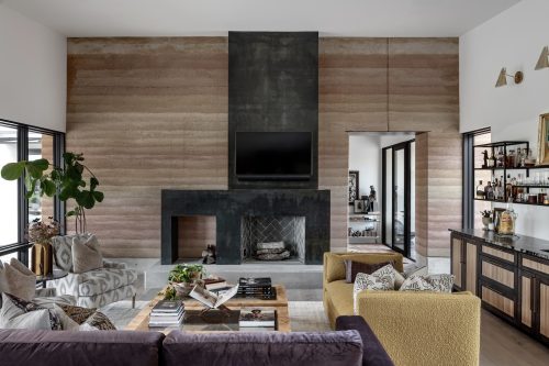 Eclectic living space with natural wood floors, warm neutral tones, and large windows framing outdoor views