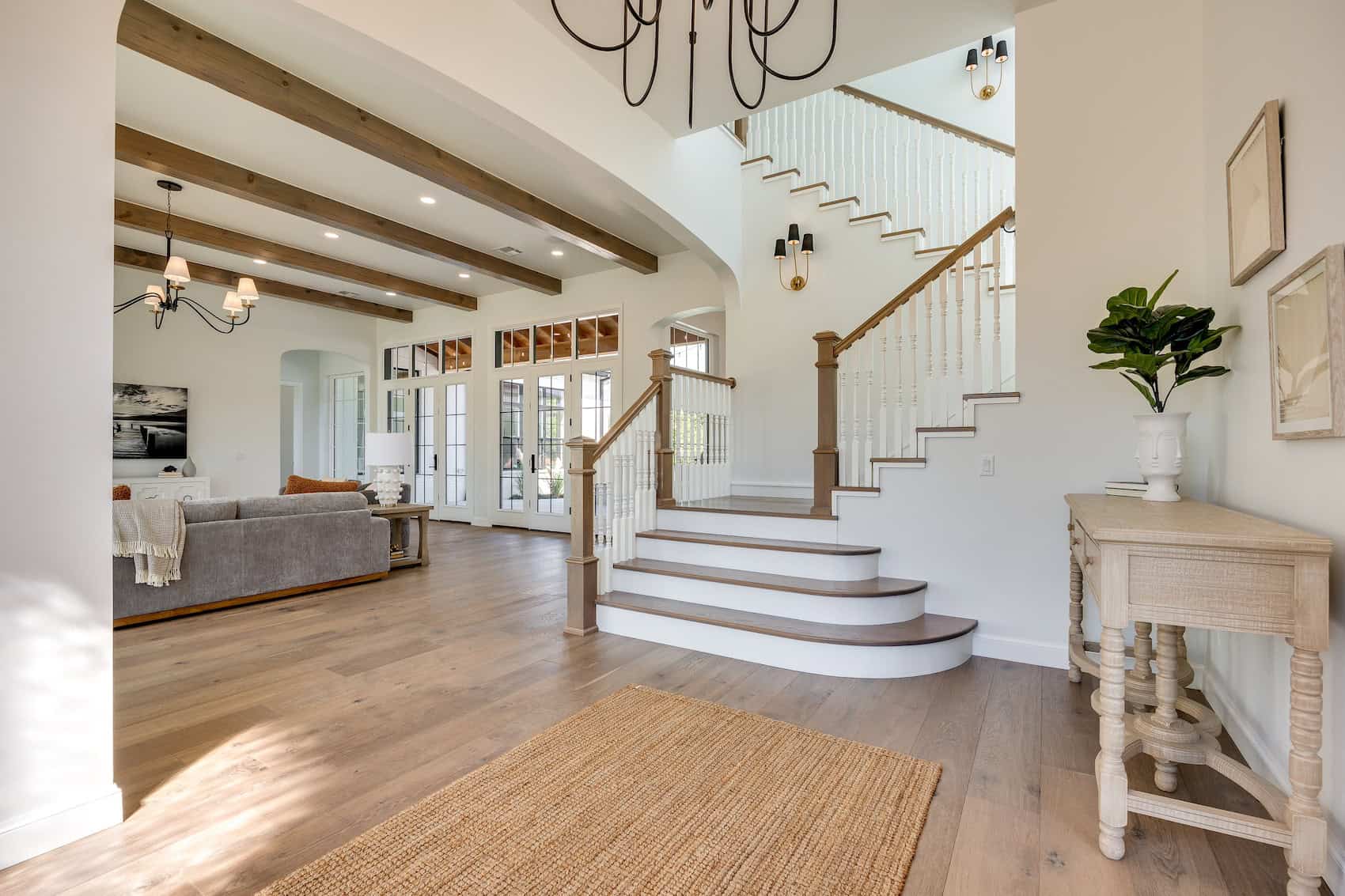 Entryway featuring a statement staircase and neutral interior grounded by warm brown wood flooring.