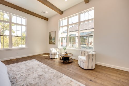 Warm modern bedroom with vaulted ceilings and wide-plank hardwood flooring.