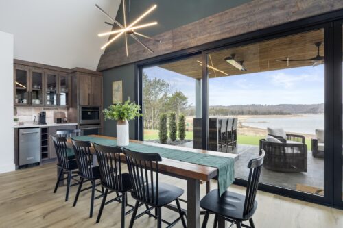 Dining area with large sliding glass doors opening to lakefront patio and continuous Retrospect - Lily Pond flooring.