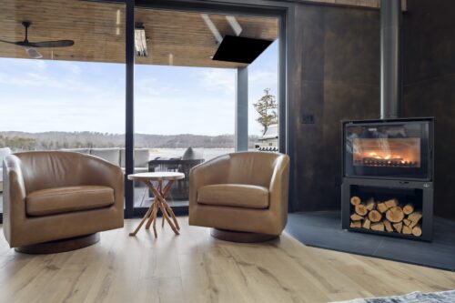 Lakefront cabin interior with expansive windows, textured seating, and warm neutral flooring