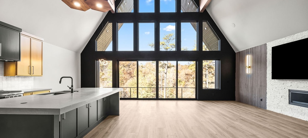 Open-concept A-frame living space with wide windows and wide plank flooring