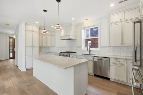 Kitchen with large island, white cabinetry, and natural Silvian wood flooring