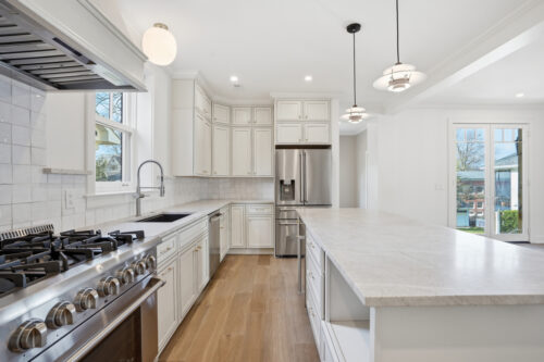 White kitchen with pendant lighting and continuous wood floors