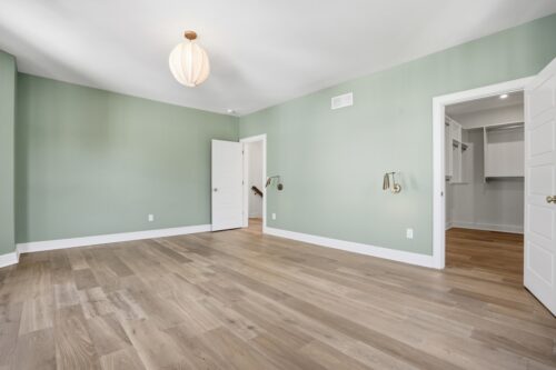 Light-filled bedroom with cohesive flooring and green painted walls