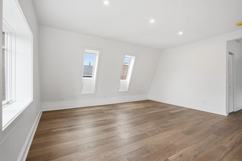 Light-filled bedroom with cohesive flooring and soft white painted walls