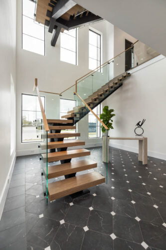 Riverstone home entryway with wide plank oak flooring, black tile and custom stair treads