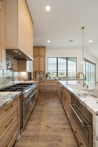 Modern kitchen with hardwood flooring and white cabinetry in Riverstone home