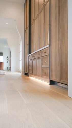 Architectural hallway with custom built-in shelving and wide-plank oak floors