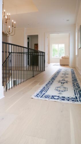 Elegant foyer with black stair railing and warm light oak flooring