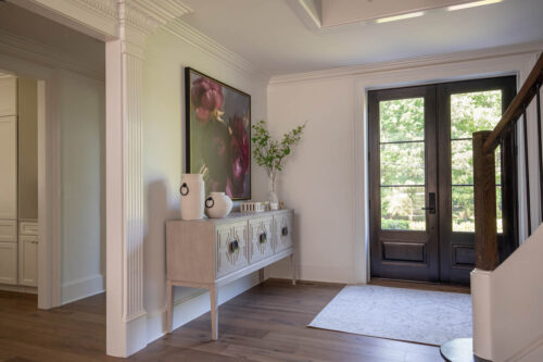 Preserved millwork and wide plank hardwood flooring create an elegant entryway in this Raleigh remodel.