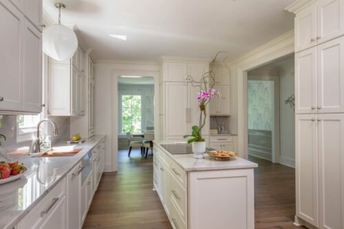 Bright kitchen featuring wide plank hardwood flooring, marble countertops, and custom cabinetry.
