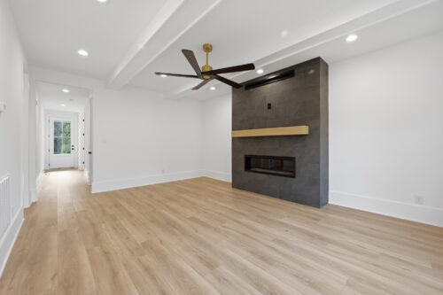 Warm wide plank flooring grounding a bright white new construction living room