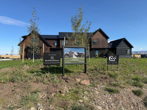 Exterior of a Bozeman, Montana home with brown and charcoal siding, gabled metal roofs, and landscaped front yard.