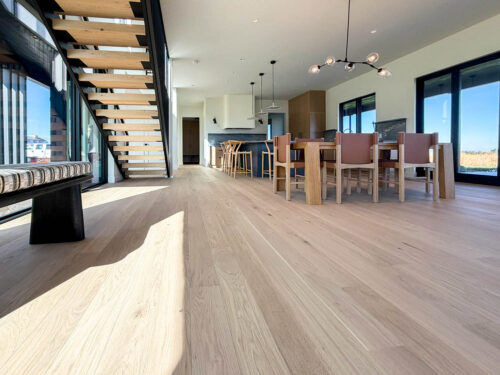 Wide plank European white oak flooring by Real Wood Floors throughout the dining area of a Bozeman home.