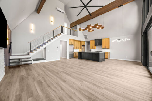 A-frame living room with vaulted ceilings, bright light, and natural-toned wood flooring overlooking a lake