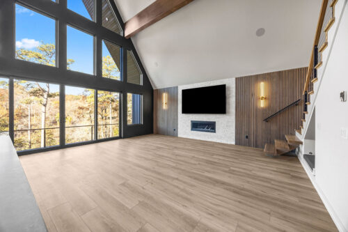 Lakefront cabin interior with expansive windows, textured walls, and warm neutral flooring