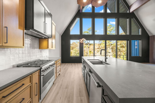 Open-concept A-frame living space with wide windows and wide plank flooring
