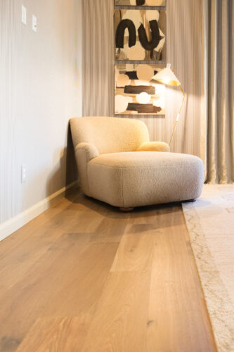 Silvian Luonto European white oak flooring complements a cream boucle lounge chair and contemporary artwork in a Collierville home.